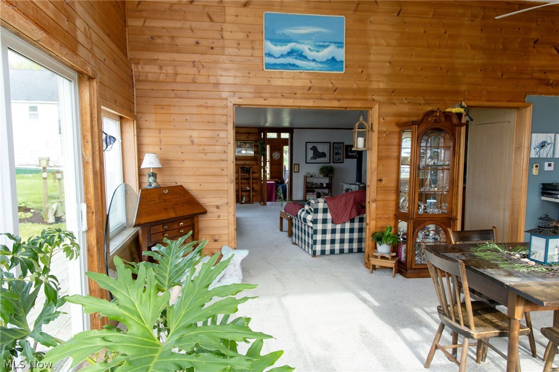 5467 Chapel Road Madison, OH 44057 - Photo 27 of 50 Sunroom with wood-paneled walls and ceiling, large windows, and light-colored carpeting