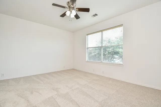 an empty room with a window and a fan