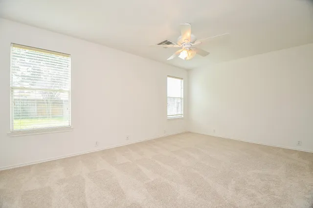 an empty room with windows and fan