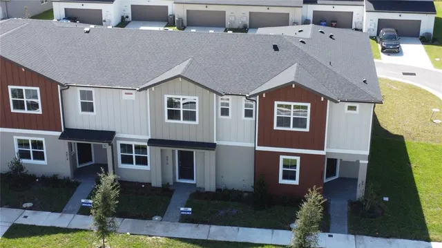 a aerial view of residential houses with yard and car parked