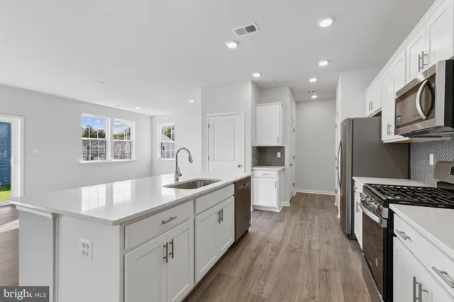 a kitchen with kitchen island granite countertop a sink cabinets stainless steel appliances and a window