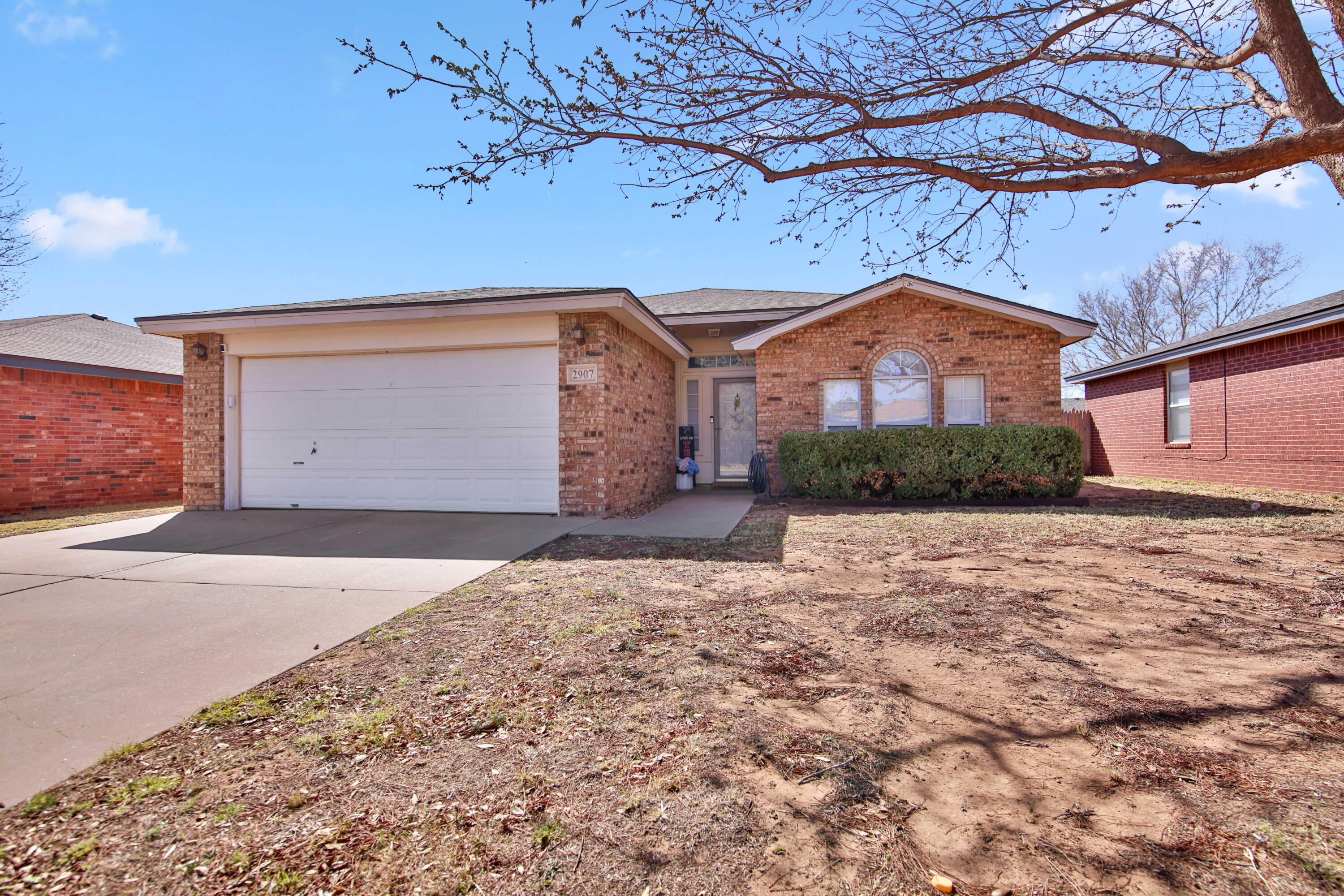 2907 90th Street Lubbock, TX 79423 - Photo 2 of 30 a front view of a house with a yard and garage
