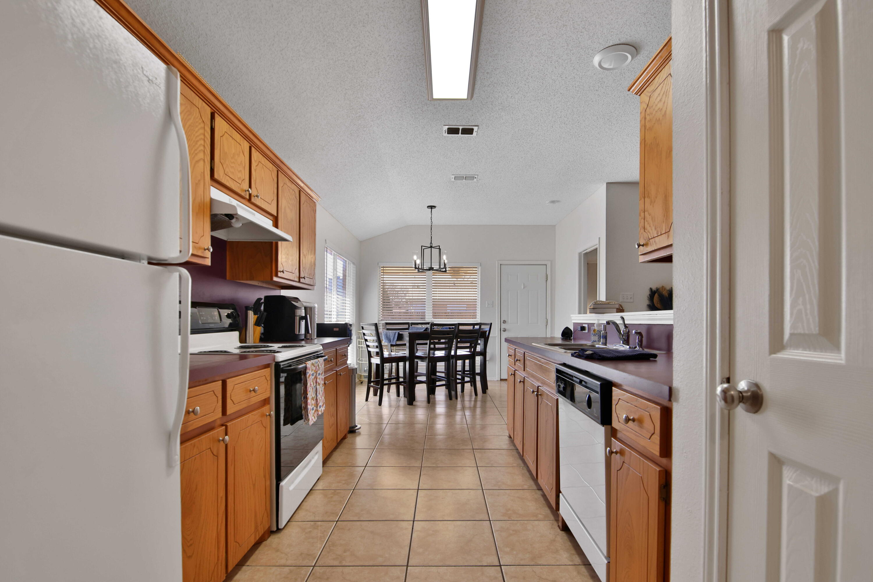 2907 90th Street Lubbock, TX 79423 - Photo 27 of 30 a kitchen with stainless steel appliances granite countertop a stove top oven a sink a dining table and chairs with wooden floor