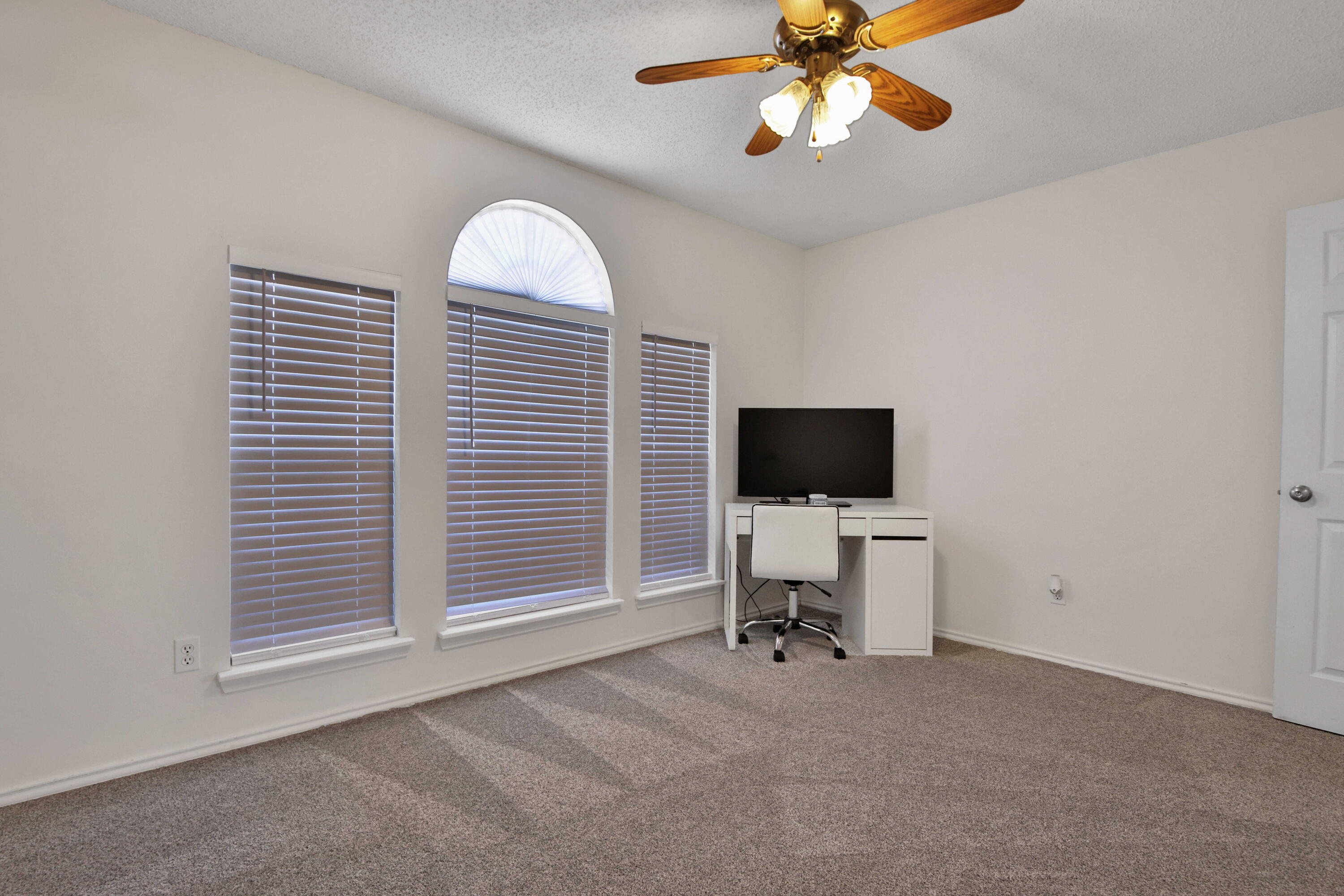 2907 90th Street Lubbock, TX 79423 - Photo 7 of 30 a view of a livingroom with a flat screen tv wooden floor and a ceiling fan