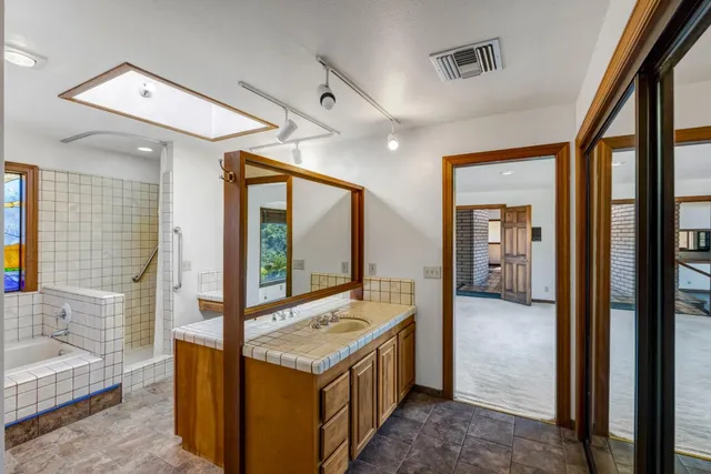 a spacious bathroom with a granite countertop double vanity sink a mirror and a bathtub