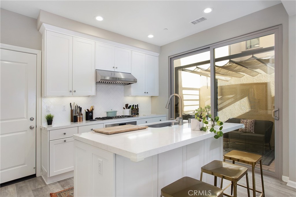 128 Nature Walk Irvine, CA 92618 - Photo 7 of 24 a kitchen with stainless steel appliances a sink a stove and white cabinets with wooden floor