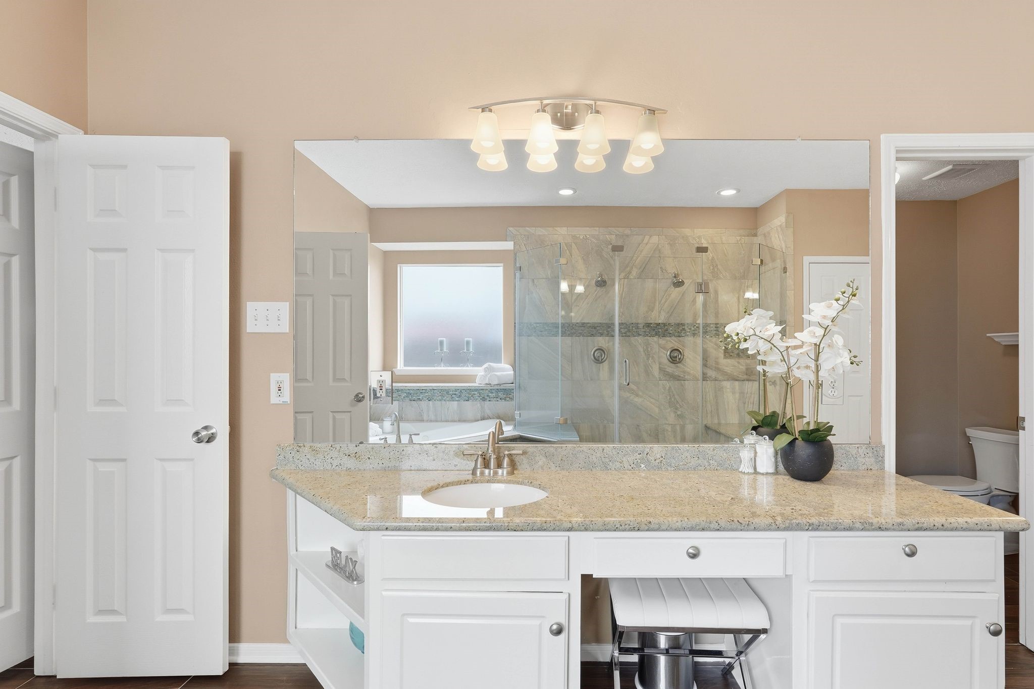 2515 Woodsboro Drive Spring, TX 77388 - Photo 20 of 44 This primary bathroom features a spacious vanity with granite countertop, large mirror, and ample storage. It includes a glass-enclosed shower with modern fixtures and a separate toilet area, offering a clean and elegant design.