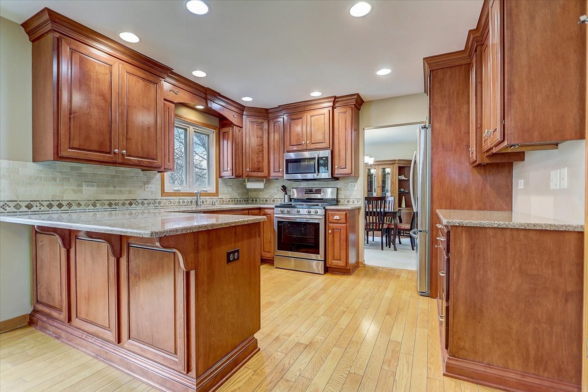 827 Manchester Street Naperville, IL 60563 - Photo 6 of 48 a kitchen with stainless steel appliances granite countertop wooden cabinets a refrigerator a sink a stove a microwave and wooden floors