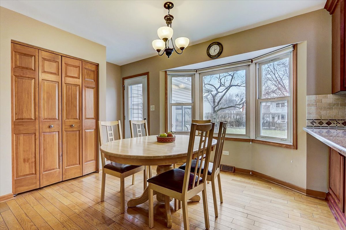 827 Manchester Street Naperville, IL 60563 - Photo 10 of 48 a dining room with wooden floor a chandelier a wooden table and chairs