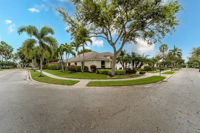 a view of a house with a big yard and palm trees