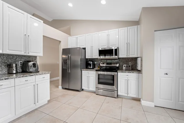 a kitchen with stainless steel appliances granite countertop a refrigerator and a stove top oven