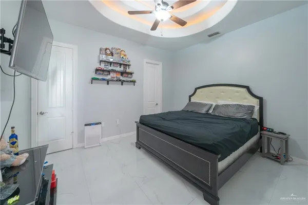 a spacious bedroom with a bed and a flat tv screen