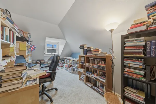 a work room with furniture a bookshelf and a window