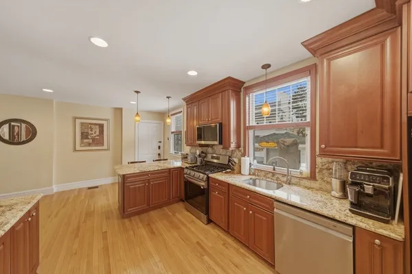 a large kitchen with stainless steel appliances granite countertop a sink and wooden cabinets