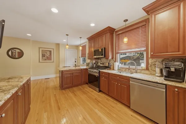a large kitchen with stainless steel appliances granite countertop a stove a sink dishwasher and a refrigerator with wooden floor