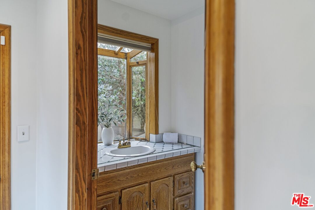 20650 Stagg Street Winnetka, CA 91306 - Photo 32 of 42 a bathroom with a granite countertop sink and a mirror