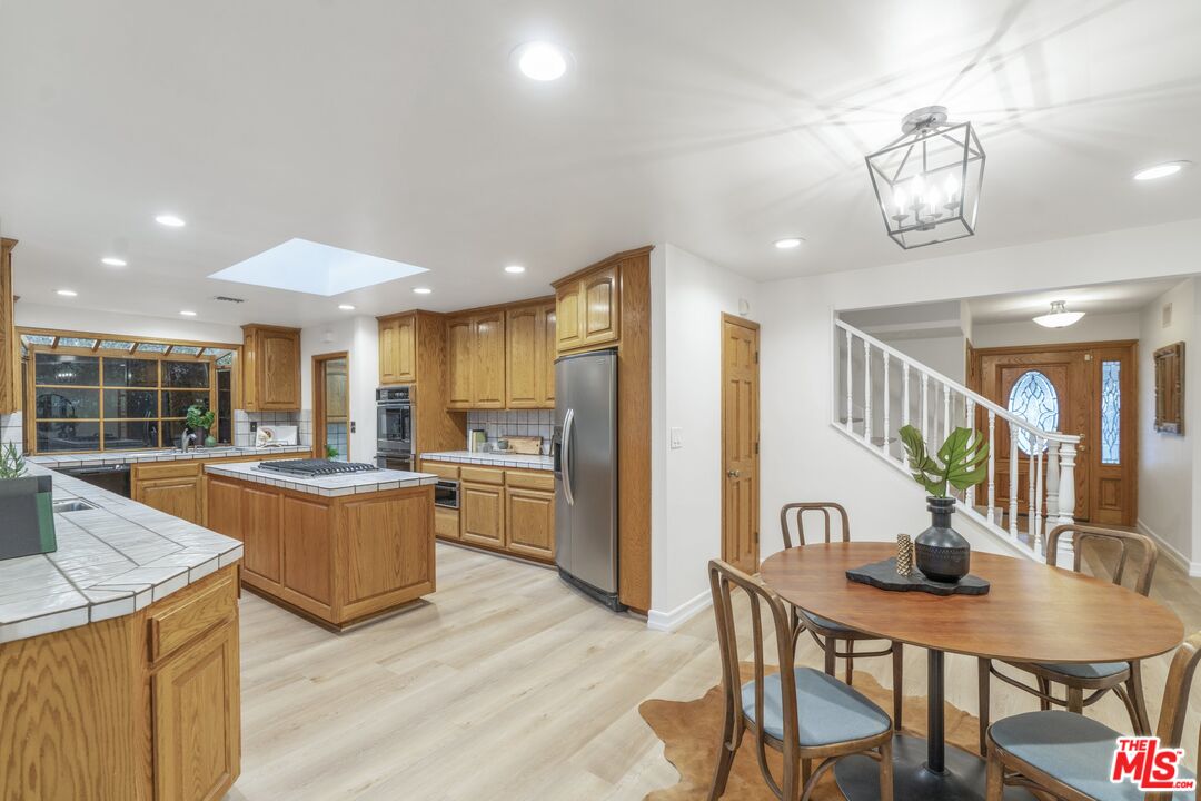 20650 Stagg Street Winnetka, CA 91306 - Photo 9 of 42 a kitchen with stainless steel appliances granite countertop a kitchen island a stove a table and chairs