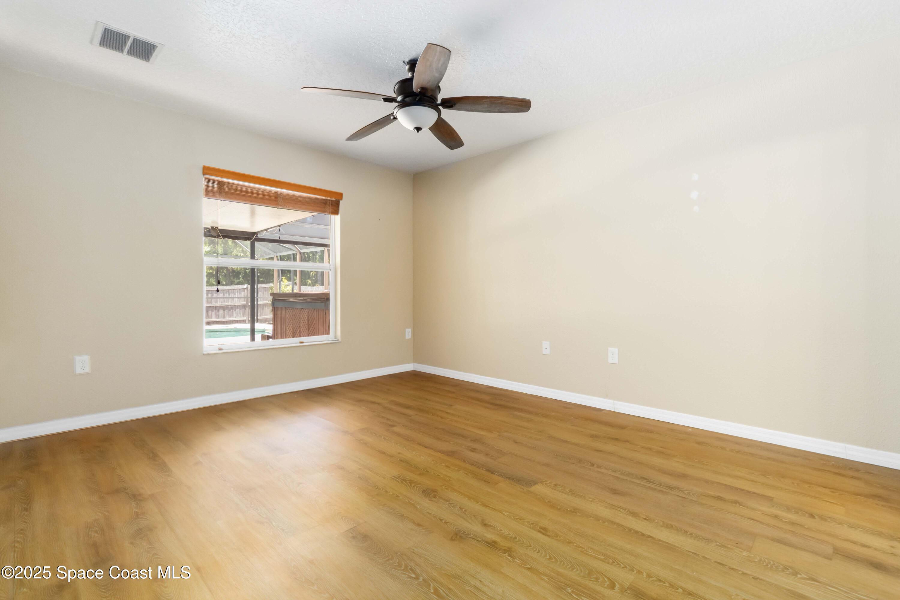 5230 Everett Street Cocoa, FL 32927 - Photo 22 of 29 an empty room with wooden floor fan and windows