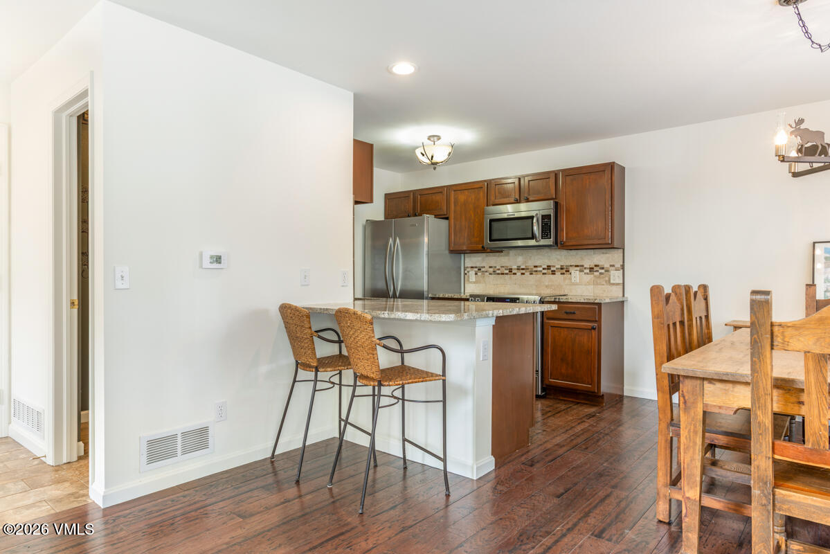 39 Red Tail Drive Edwards, CO 81632 - Photo 7 of 24 a kitchen with stainless steel appliances granite countertop a stove top oven a sink dishwasher a dining table and chairs with wooden floor