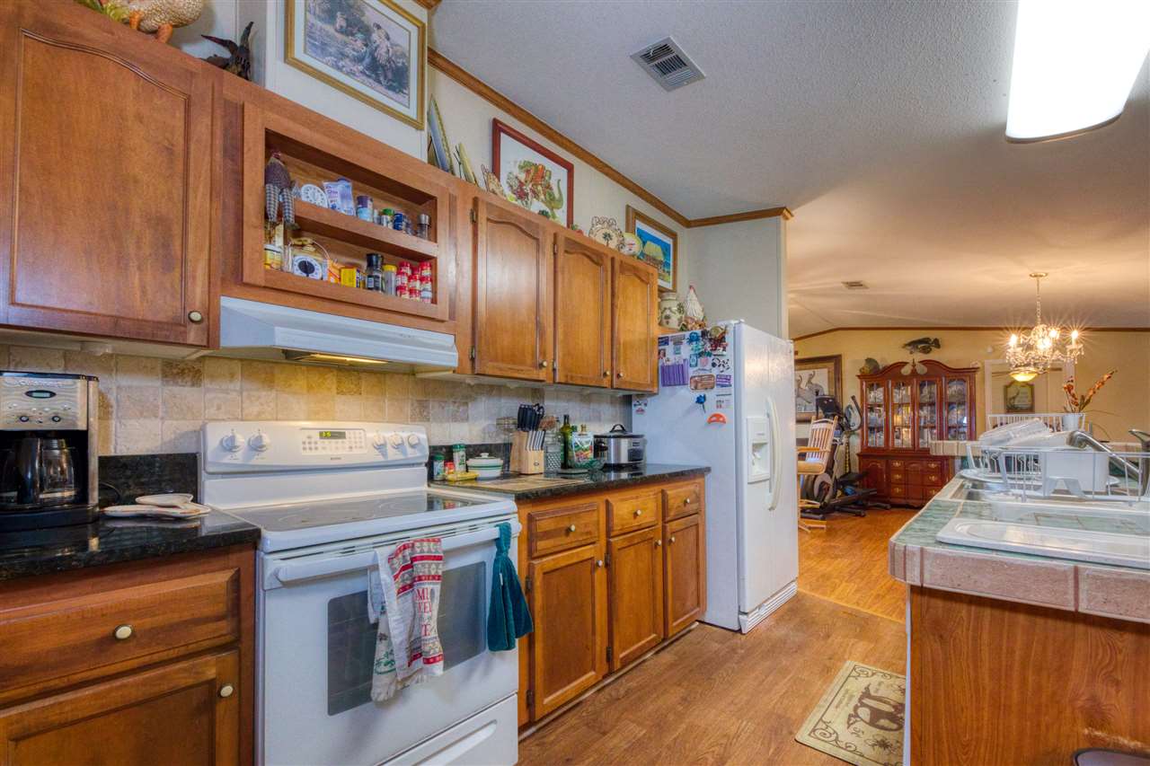 8580 G Palmo Fish Camp Road St. Augustine, FL 32092 - Photo 40 of 48 a kitchen with stainless steel appliances granite countertop a stove a sink dishwasher and cabinets with wooden floor