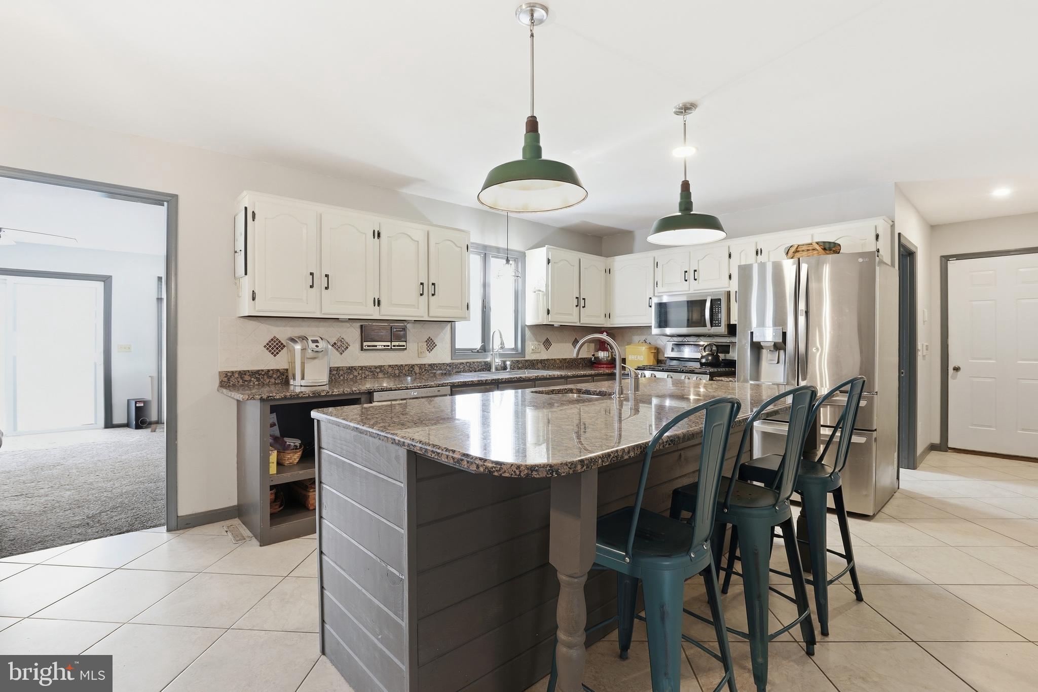 228 Firetower Road Camden Wyoming, DE 19934 - Photo 13 of 39 a kitchen with stainless steel appliances kitchen island granite countertop a table chairs and a refrigerator