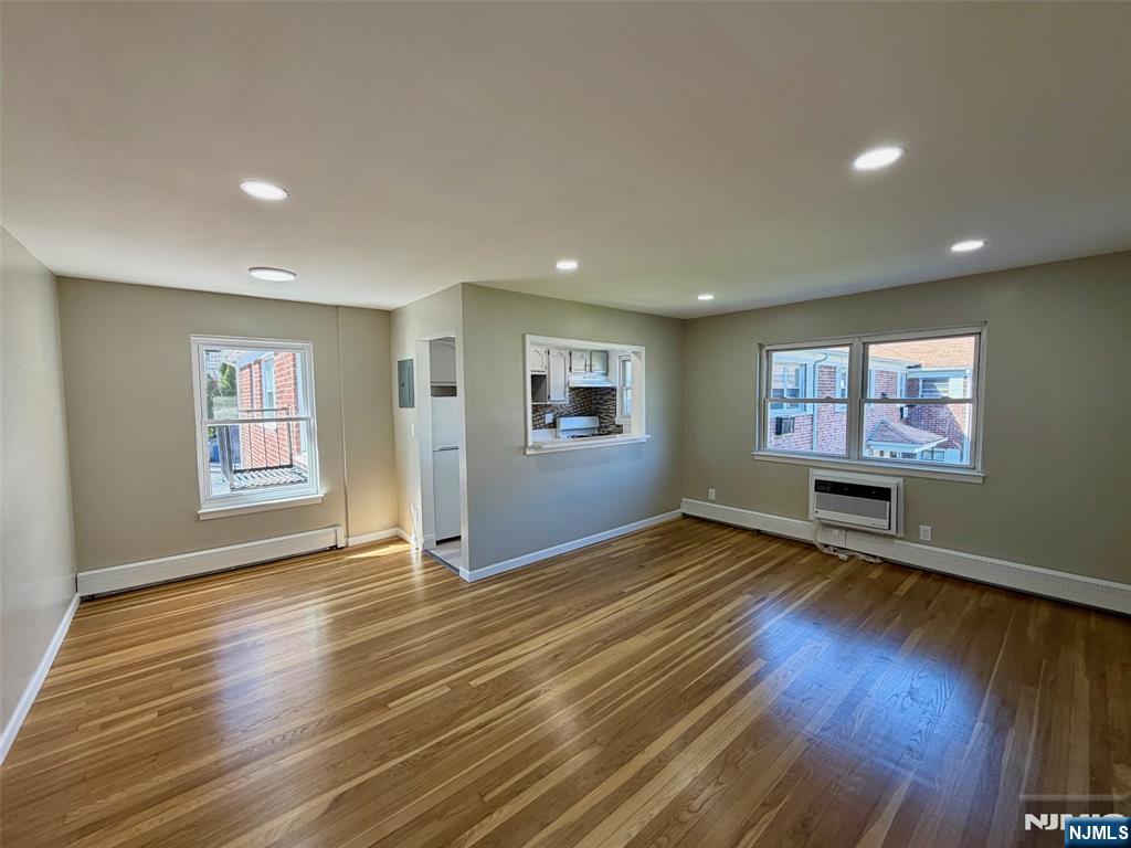 a view of an empty room with window and wooden floor