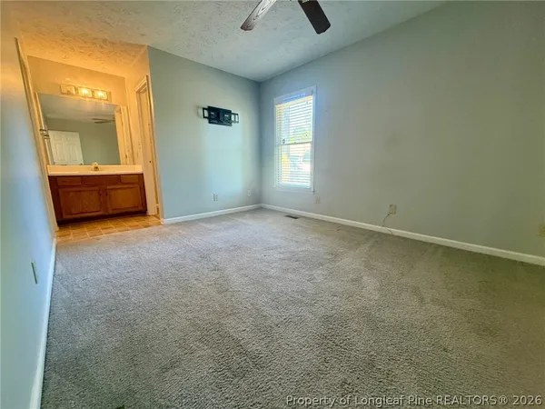 an empty room with chandelier fan and windows