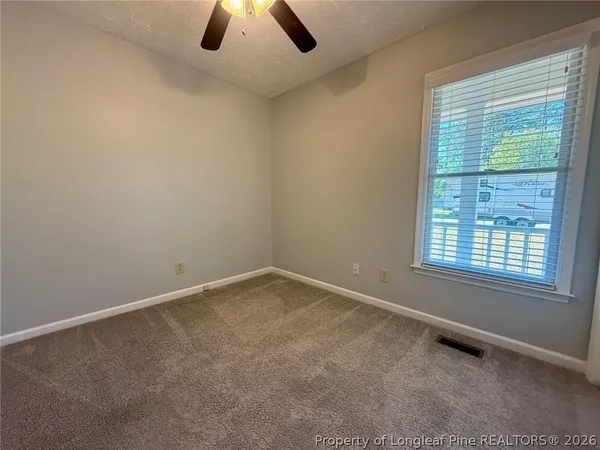 an empty room with ceiling fan and window