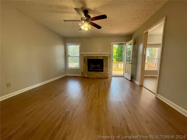 a view of a livingroom with a fireplace a ceiling fan and wooden floor