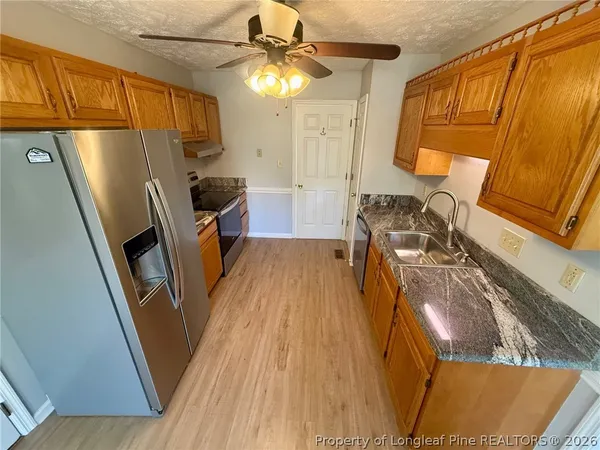 a view of a kitchen with fridge and wooden floor