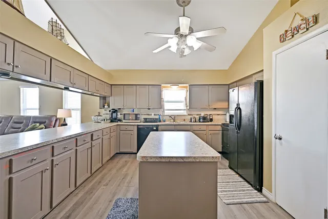 a kitchen with stainless steel appliances granite countertop a refrigerator a sink dishwasher a stove and white cabinets with wooden floor