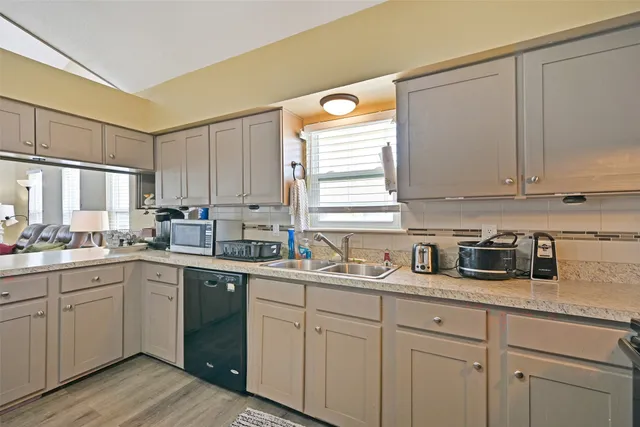 a kitchen with a sink dishwasher window and cabinets