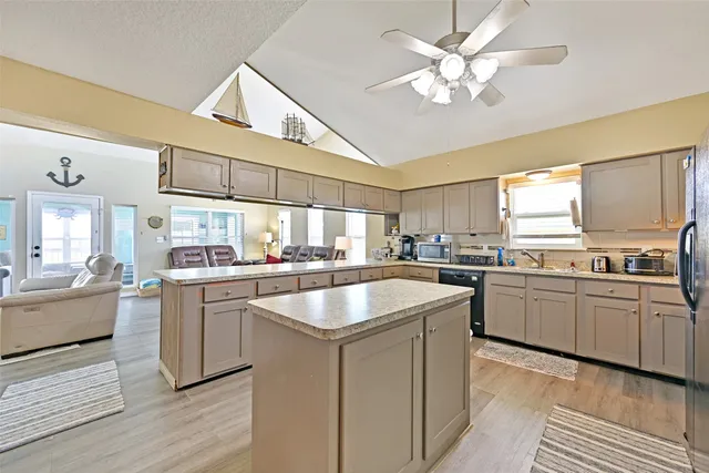 a kitchen with stainless steel appliances granite countertop a sink dishwasher stove and refrigerator with wooden floor
