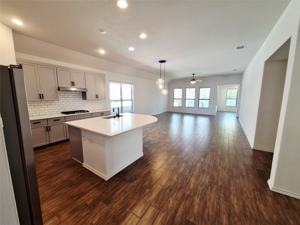 1104 River Vista Road Georgetown, TX 78628 - Photo 13 of 39 a kitchen with stainless steel appliances a white stove top oven a sink dishwasher and a refrigerator with wooden floor