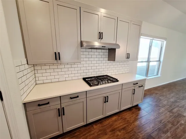 a kitchen with stainless steel appliances a white stove top oven cabinets a sink and a window