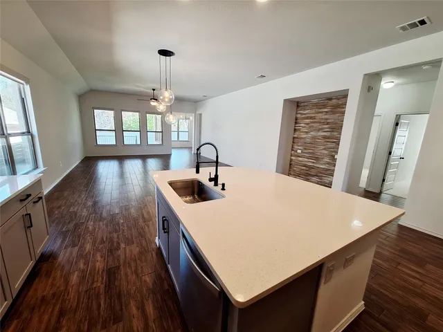 a kitchen with a wooden floor and a view of living room