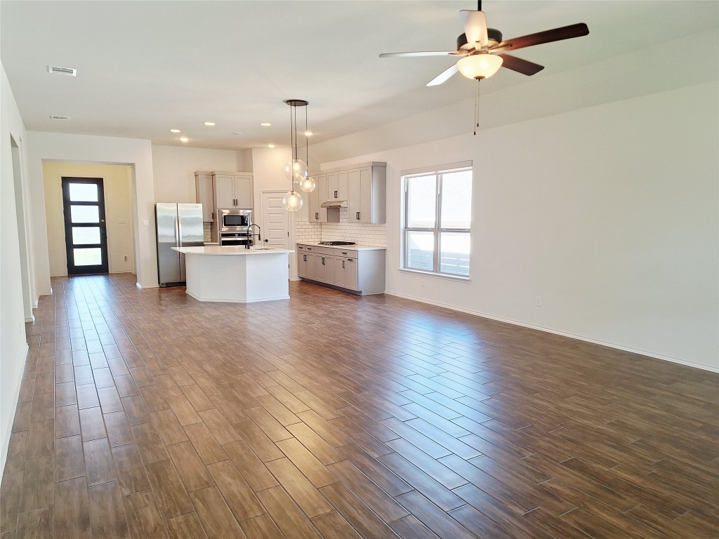 1104 River Vista Road Georgetown, TX 78628 - Photo 7 of 39 a view of a kitchen with kitchen island a sink wooden floor and a living room view
