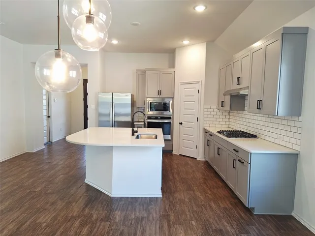 an open kitchen with wooden floor and stainless steel appliances