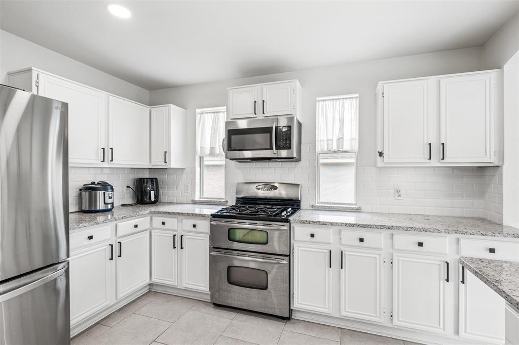 1011 Ridgecrest Drive McKinney, TX 75069 - Photo 15 of 31 Kitchen featuring stainless steel appliances, white cabinetry with dark hardware, a subway tile backsplash, and light-toned countertops