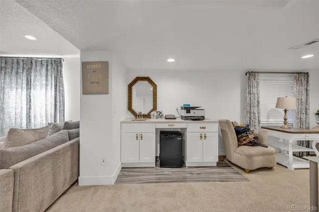 a living room with furniture a mirror and white walls