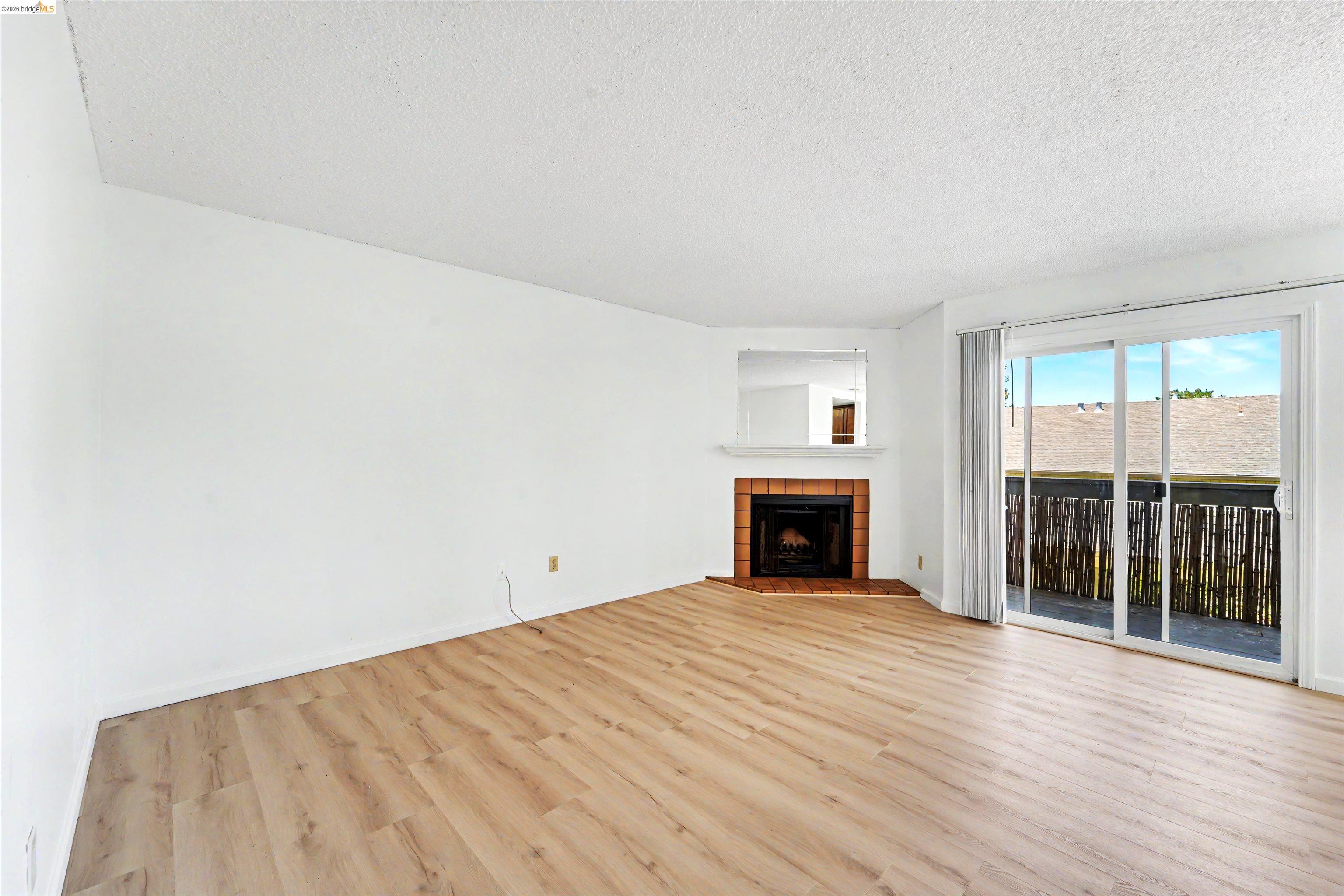 4186 San Pablo Dam Road, Unit A El Sobrante, CA 94803 - Photo 5 of 34 Living area featuring wood-finish flooring, a corner fireplace with brick surround, white mantel, and a mirrored accent