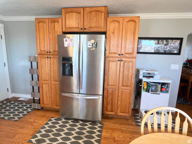 1852 East 3500th Street South Vernal, UT 84078 - Photo 12 of 46 Kitchen featuring crown molding, stainless steel fridge, light wood finished floors, wood finish cabinetry, and a textured ceiling