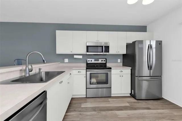 a kitchen with a refrigerator sink and white cabinets