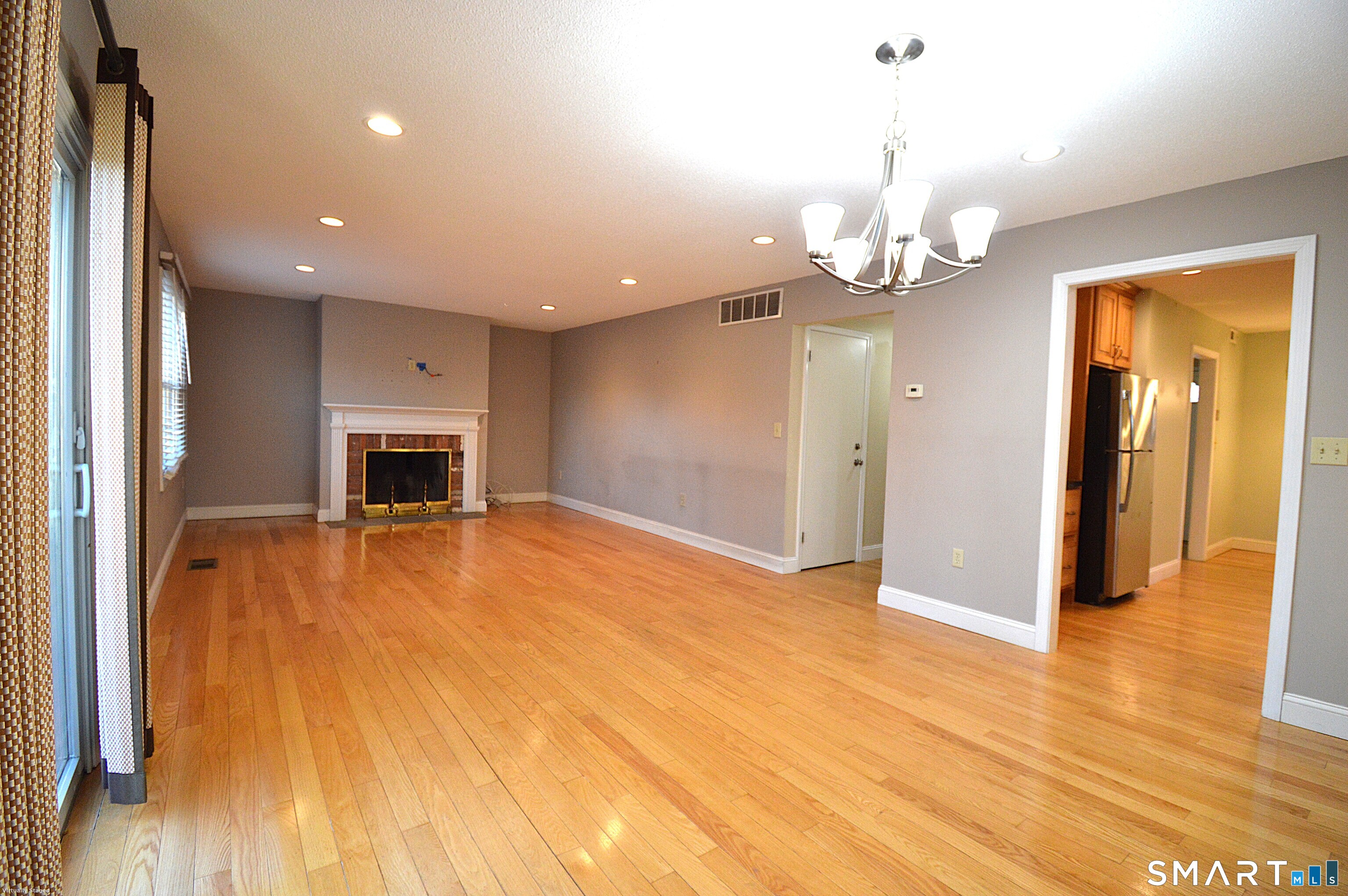 a view of a livingroom with a fireplace wooden floor and a chandelier