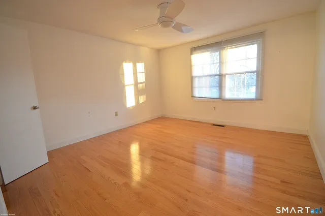 an empty room with wooden floor and windows