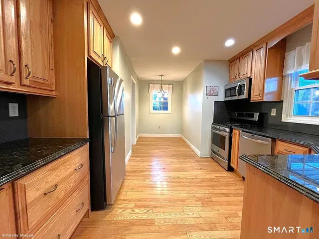 a view of a kitchen with stainless steel appliances granite countertop a refrigerator and a stove top oven