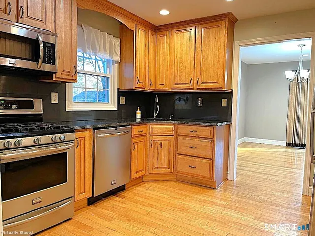 a kitchen with stainless steel appliances granite countertop a stove a sink and a microwave