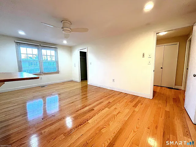 a view of an empty room with window and wooden floor