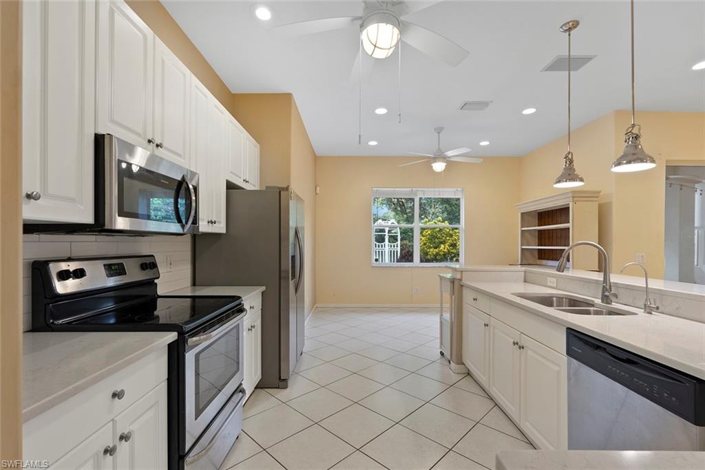 3262 Citron Drive Naples, FL 34120 - Photo 15 of 38 a kitchen with stainless steel appliances granite countertop a sink a stove a refrigerator a window and cabinets