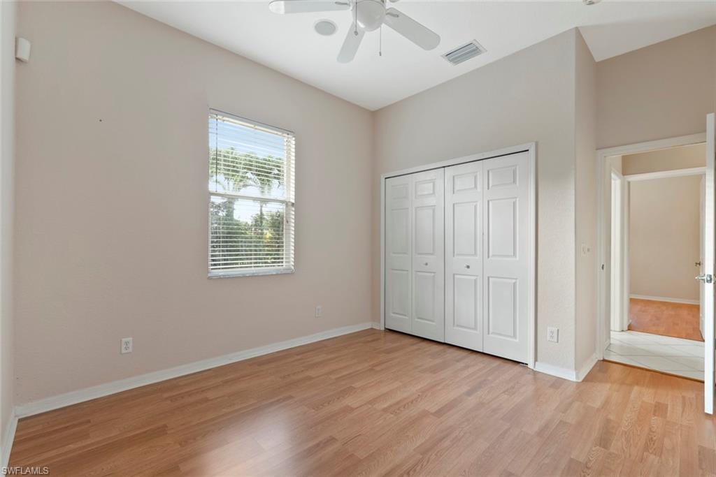3262 Citron Drive Naples, FL 34120 - Photo 19 of 38 an empty room with wooden floor chandelier fan and windows